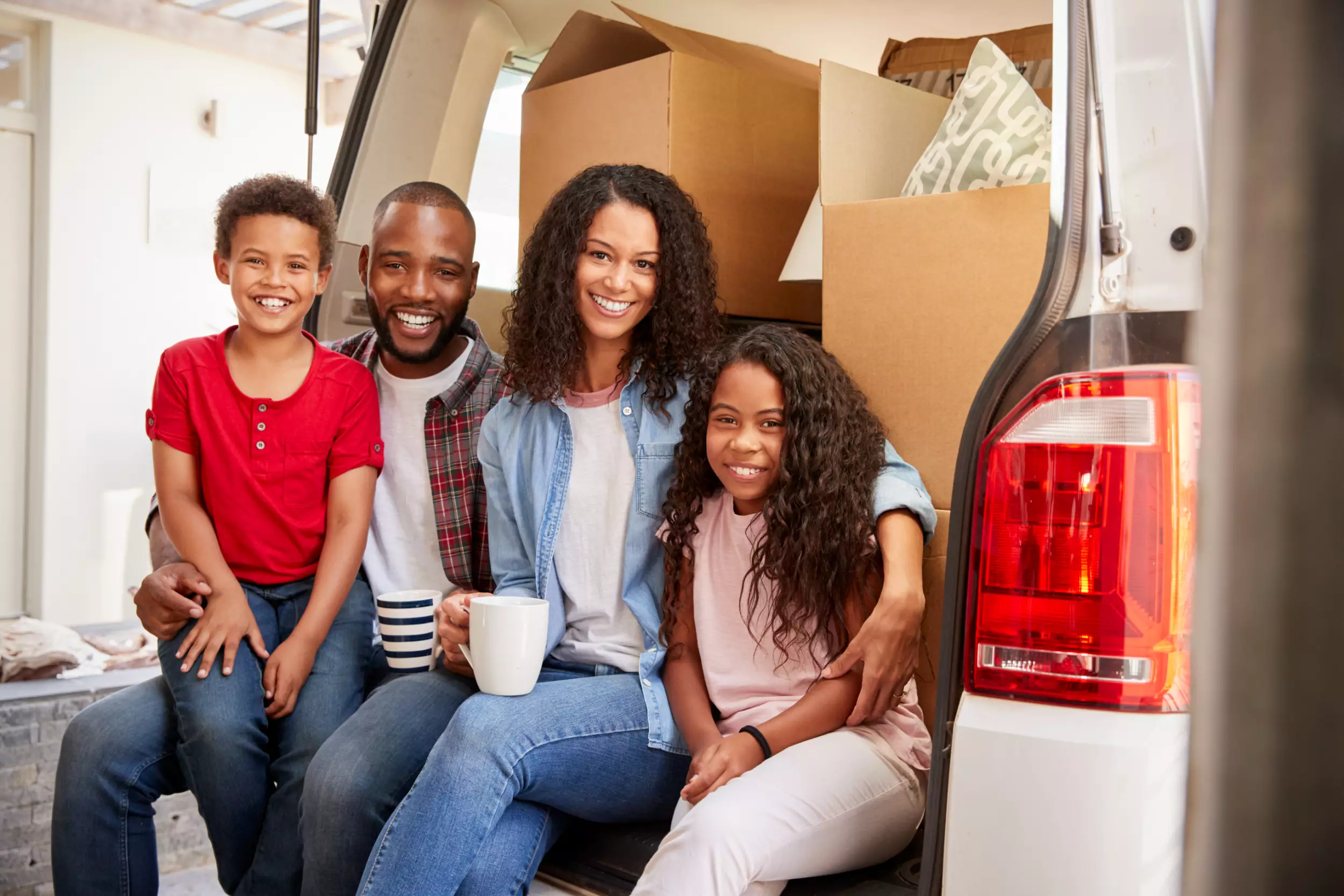 Young family with moving boxes in the back of their vehicle